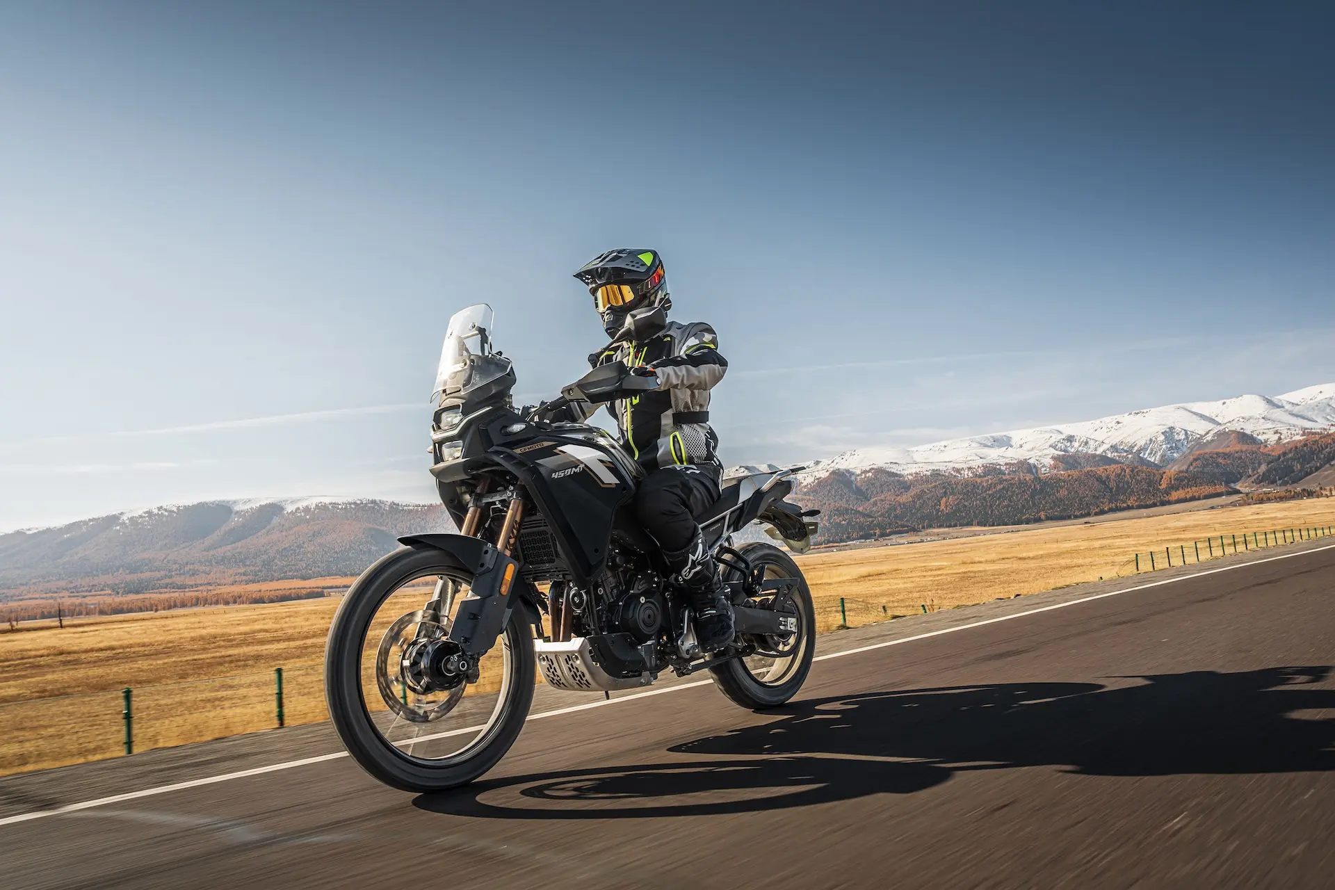 CFMOTO 450MT Nebula Black riding mountain road with autumn grasslands