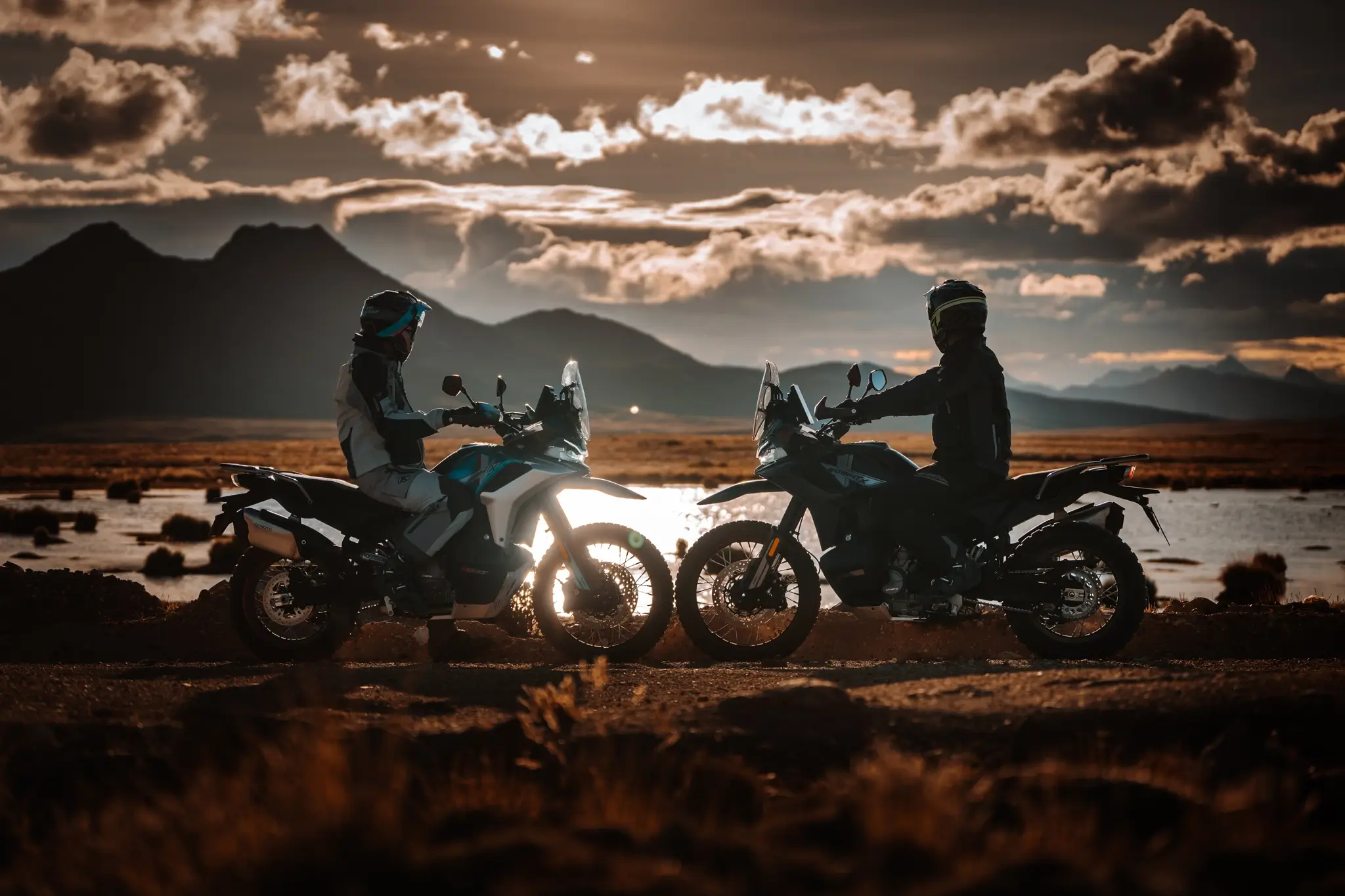 CFMOTO 800MT-X duo silhouetted at sunset with mountain backdrop