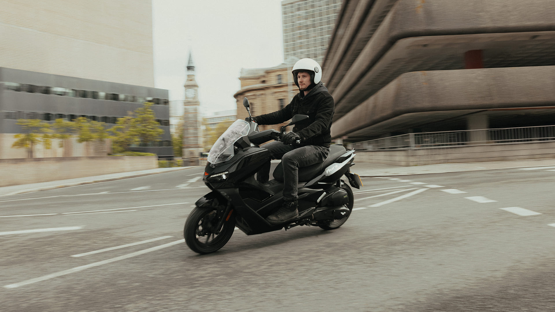 Rider on Aura 125 front three-quarter view through urban streets