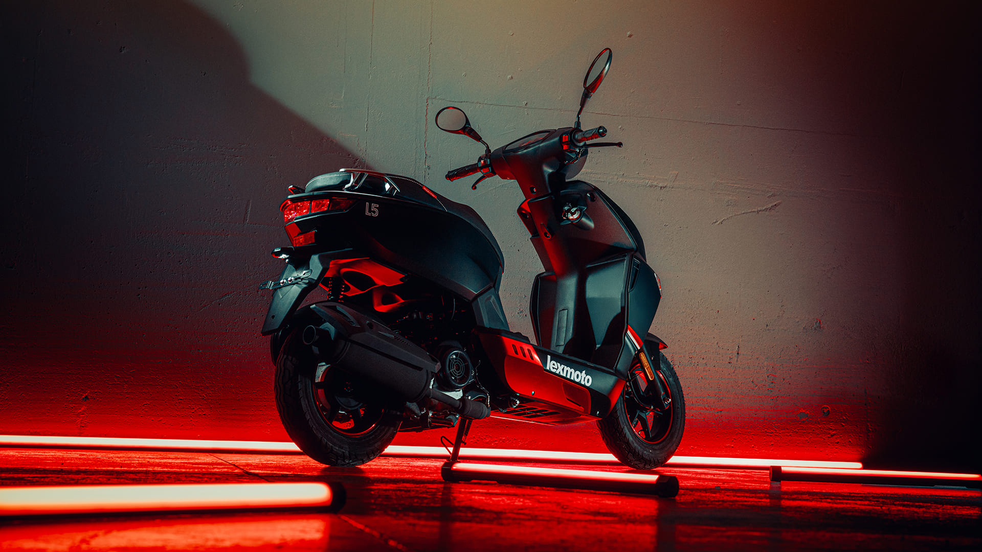 L5 rear three-quarter in dark studio with red neon tubes