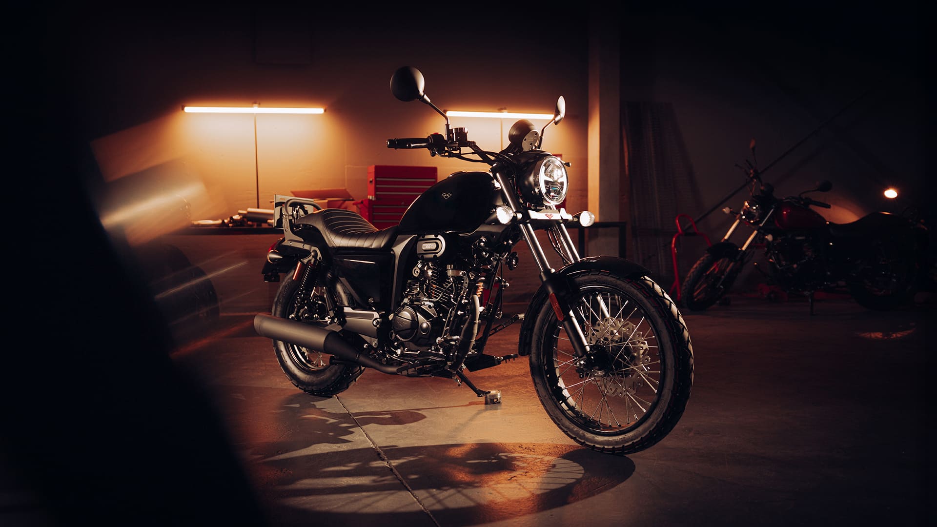 R66+ Black front view through garage with dramatic headlight beam